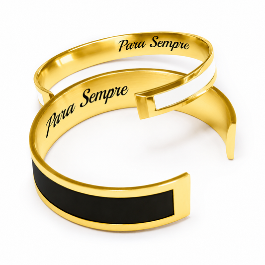 A photo of two matching bracelets, one in gold color and the other in black, with the word 'amor' and a heart symbol engraved on the gold bracelet.