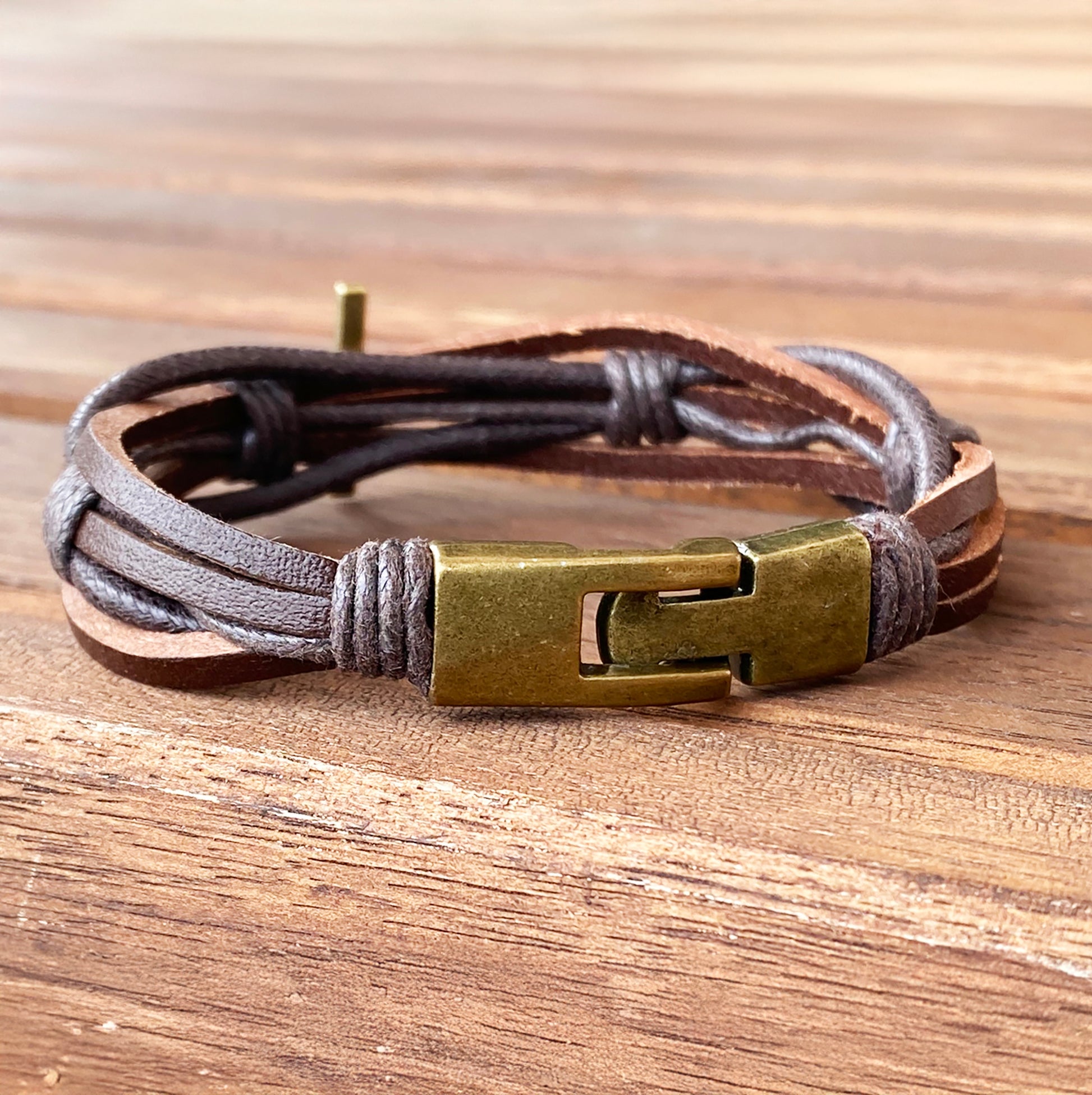 men's braided leather bracelet with brass cross and clasp on wooden table – Christian gift for him