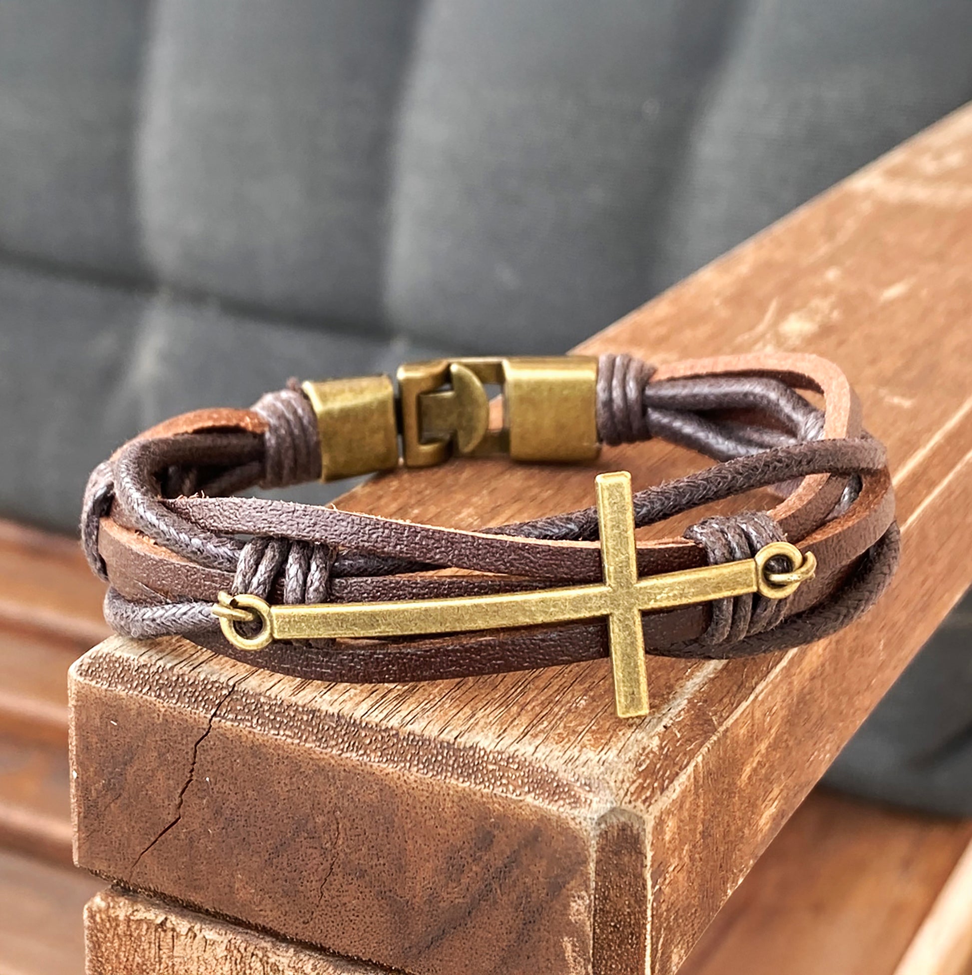 brown braided leather bracelet with brass cross on wooden bench – Christian gift for men